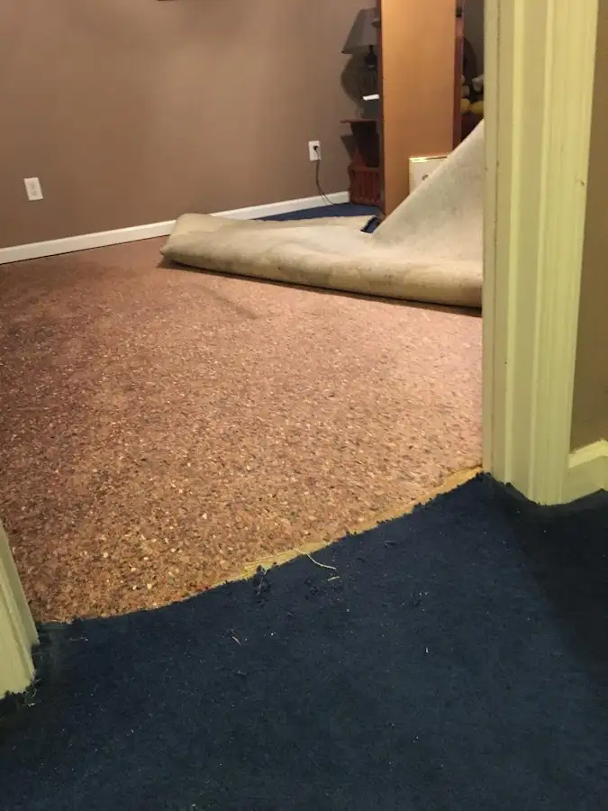Carpet pad removal revealing water damage during Water Mitigation Services in Glens Falls